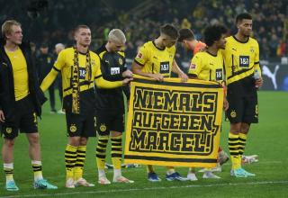 Die Spieler des BVB halten vor der Südtribüne ein Plakat in der Hand, darauf steht: "Niemals aufgeben, Marcel!".

