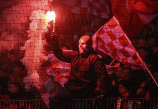 Ein vermummter Fan des FC Energie Cottbus zündet Pyrotechnik.