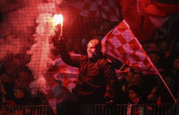 Ein vermummter Fan des FC Energie Cottbus zündet Pyrotechnik.